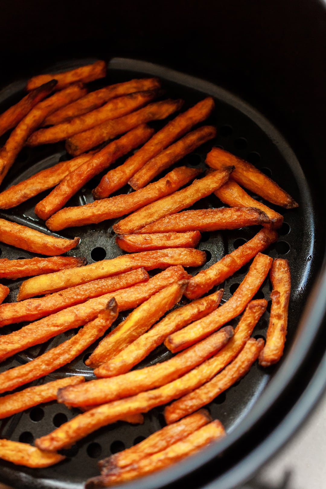 cooked frozen sweet potato fries in an air fryer basket 