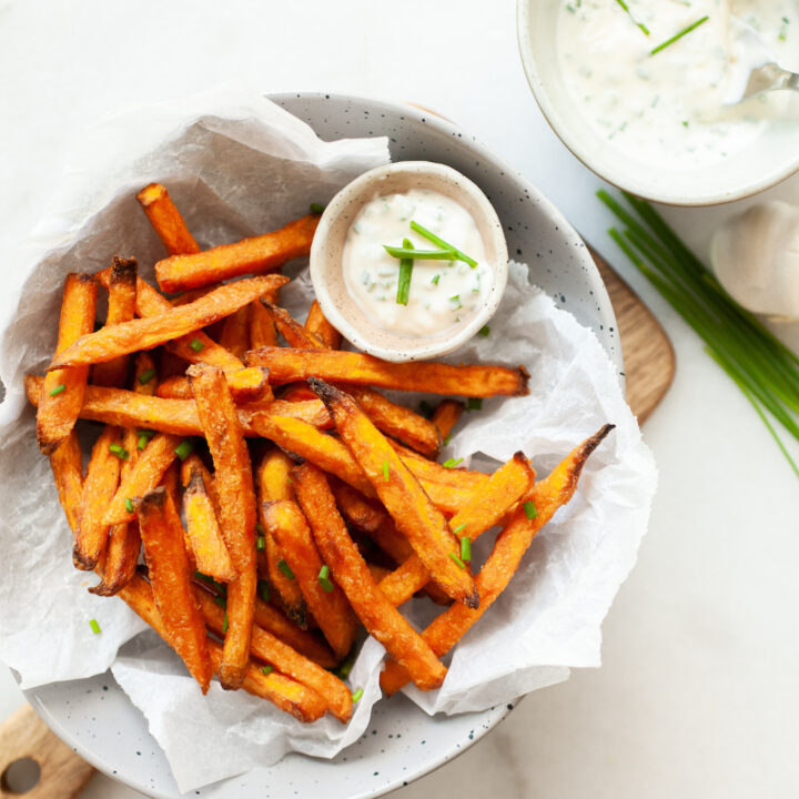 cooked air fryer sweet potato fries in a bowl with chive dipping sauce on the side