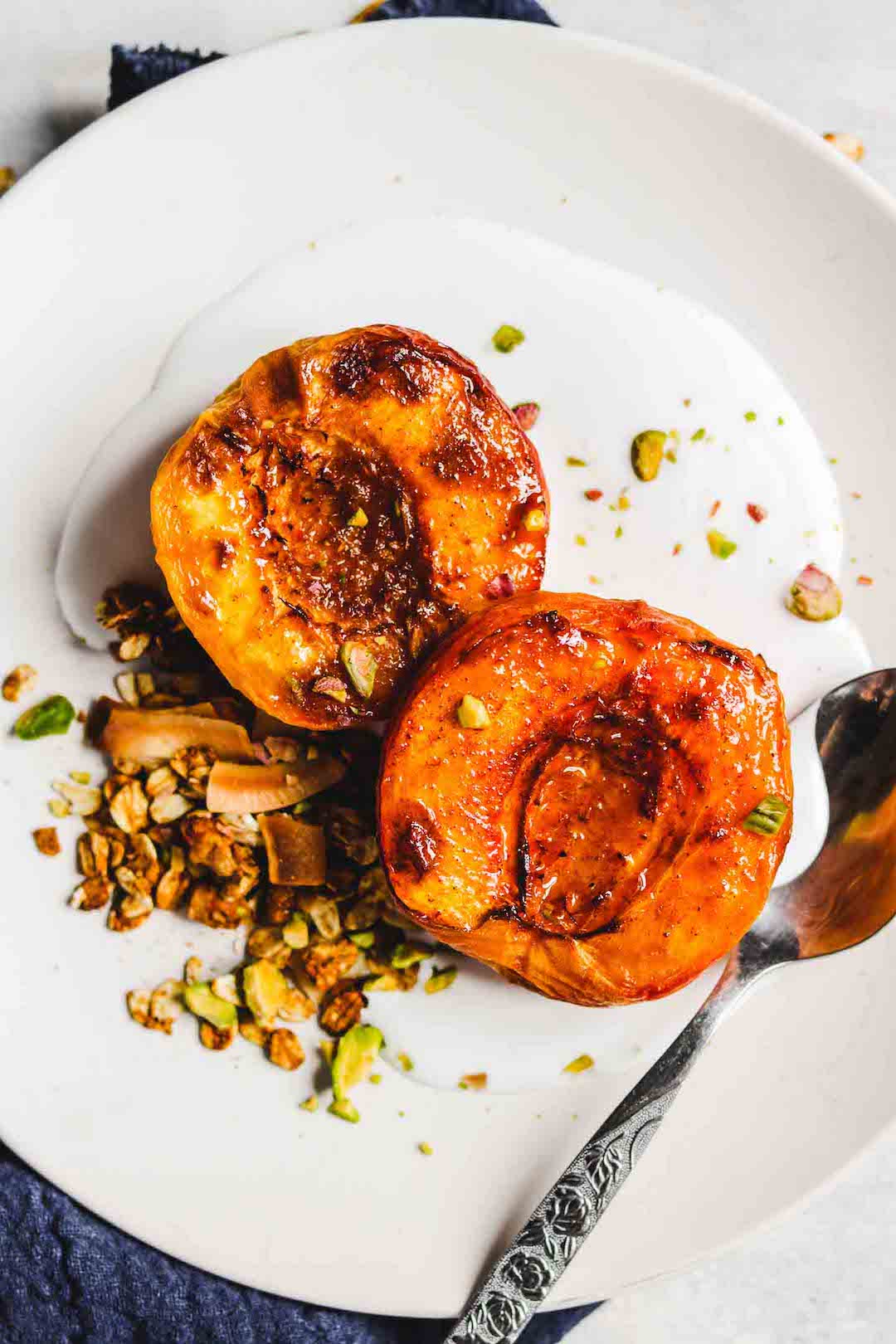 image of two air fried stone fruits on a plate with pistachios