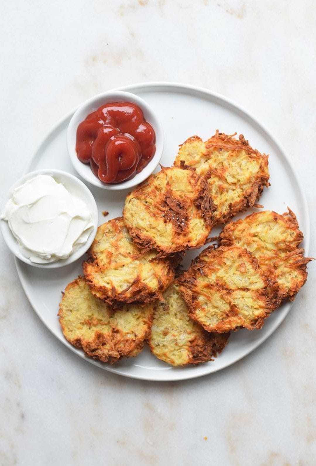 image of a white plate with air fryer hashbrowns and a side of ketchup