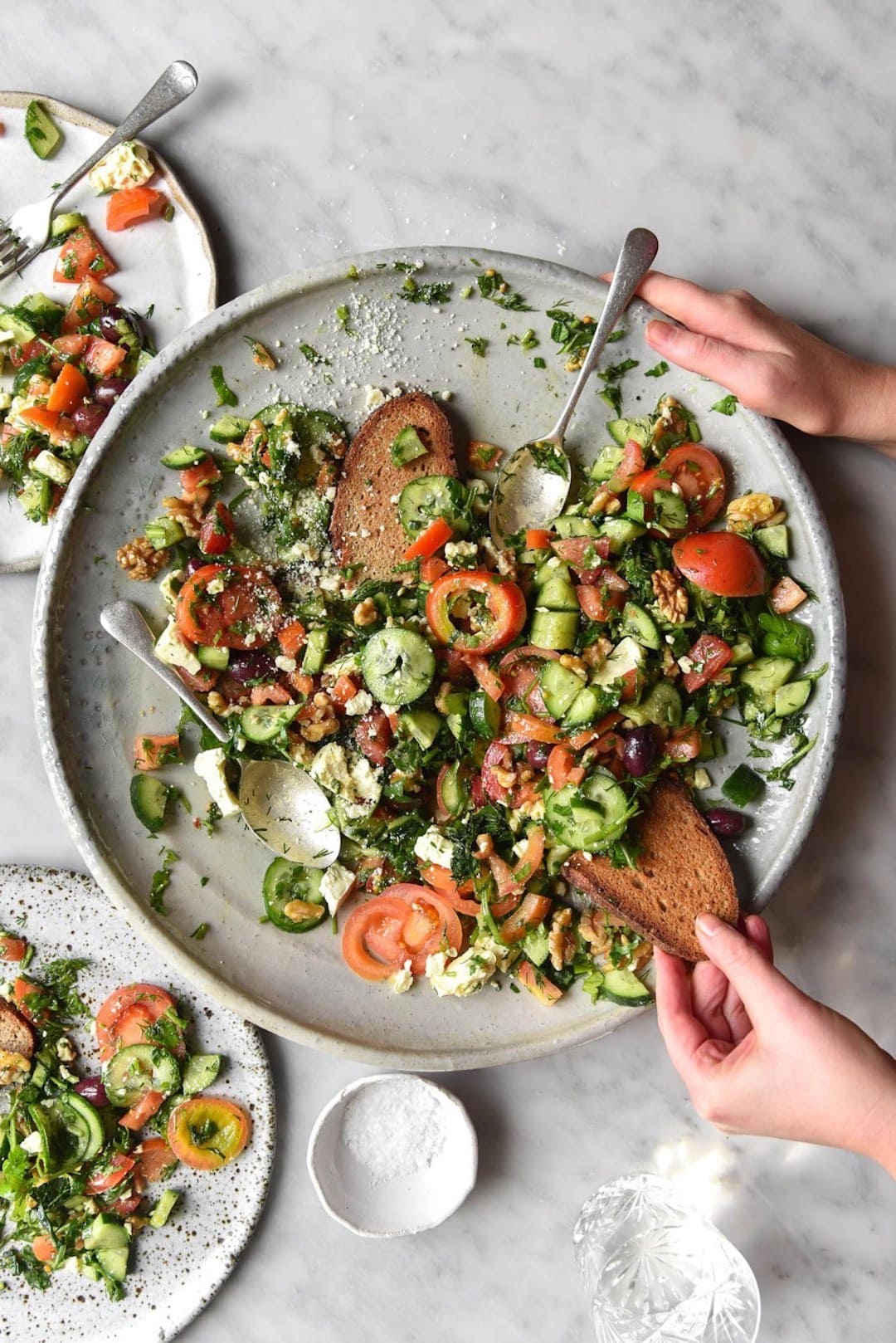 image of a large plate topped with vegetarian low fodmap cucumber tomato salad with hands holding the plate