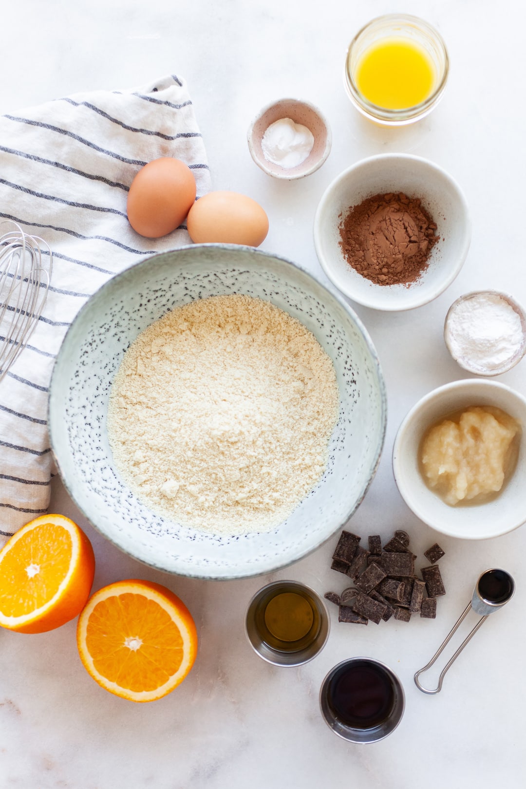 image of a flat lay of ingredients for chocolate orange cupcakes on a marble background