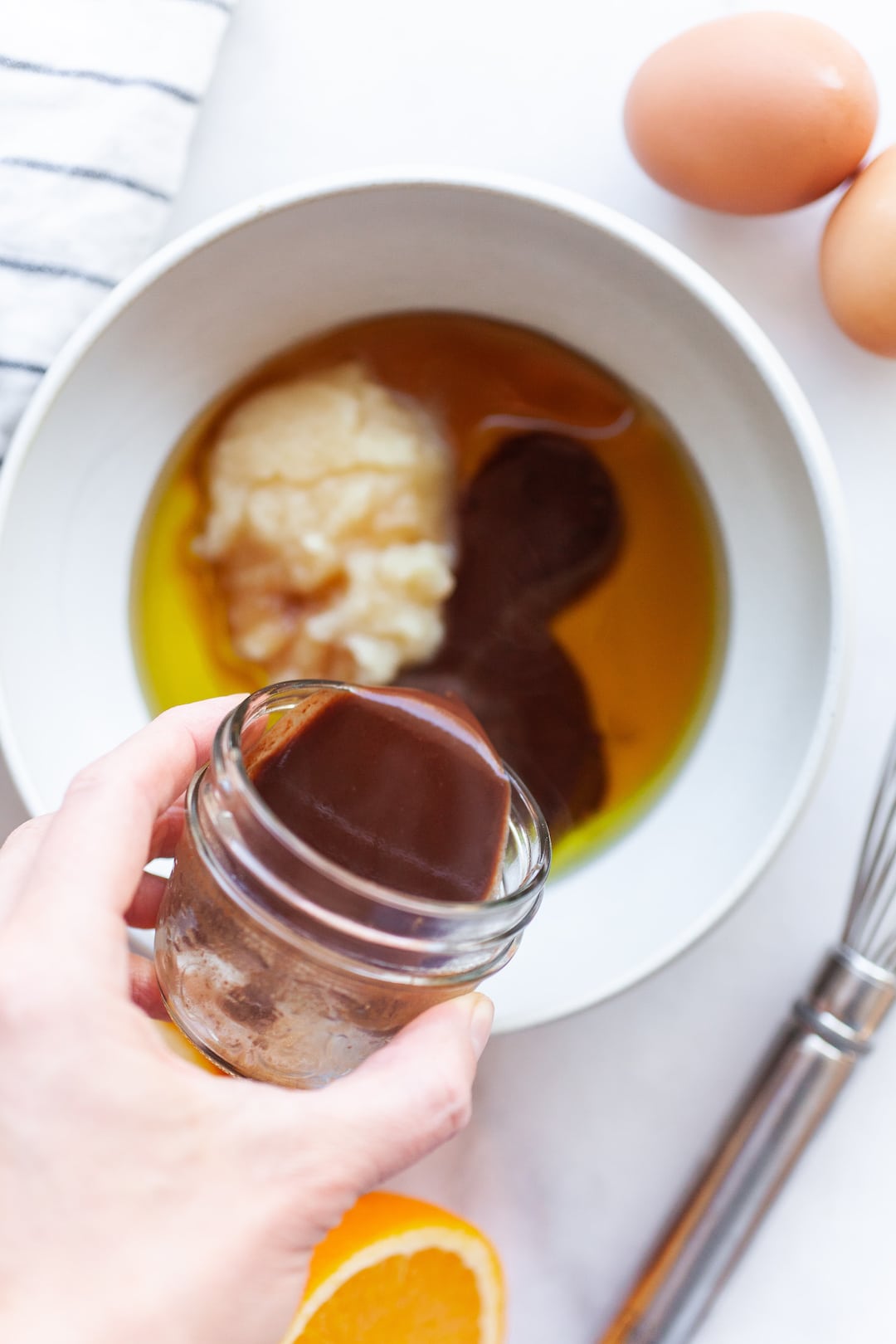image of a bowl of wet ingredients for chocolate orange cupcakes with chocolate sauce being poured in