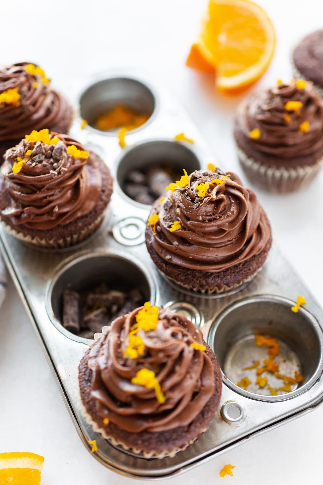 image of a small cupcake pan with 6 chocolate cupcakes topped with chocolate icing and orange zest