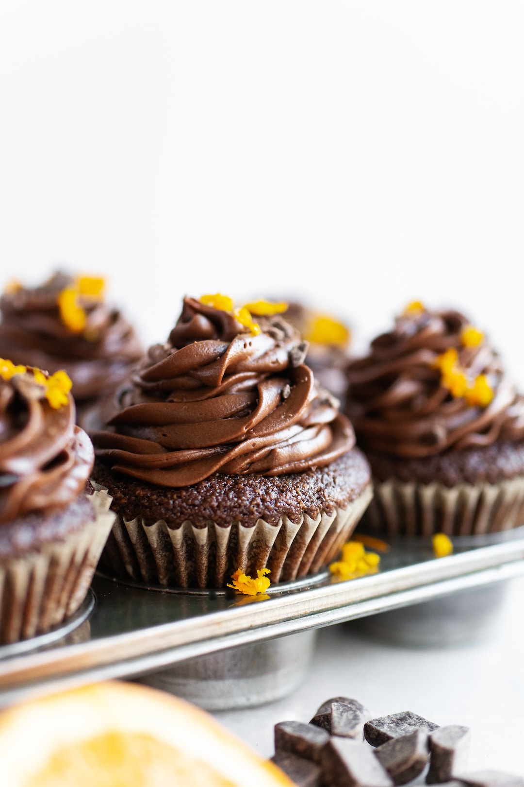 image of chocolate orange cupcakes from the side topped with orange zest and a white background