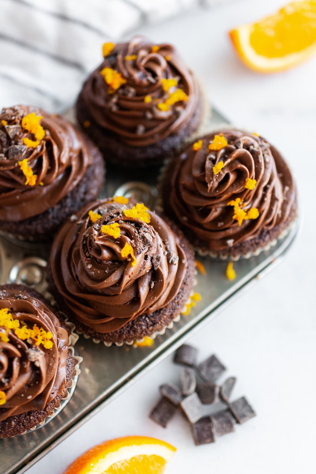 image of chocolate orange cupcakes in a small metal tin topped with orange zest