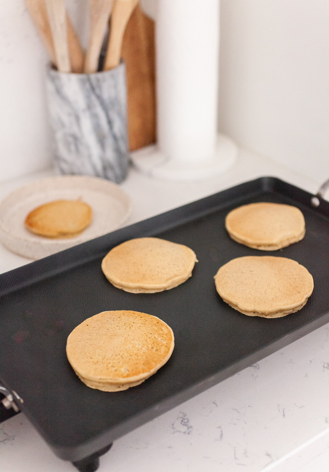 image of a black griddle in a white kitchen with pancakes on top