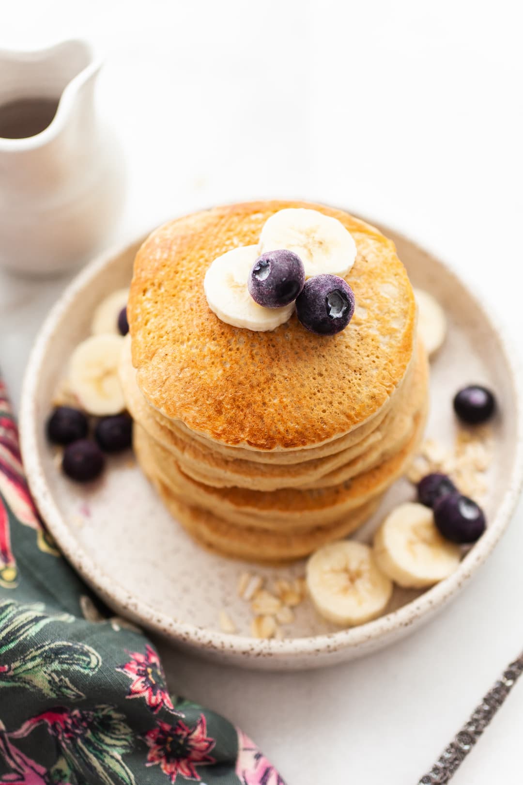 image of a stack of Fluffy Oat Flour Pancakes with blueberries and banana slices on top