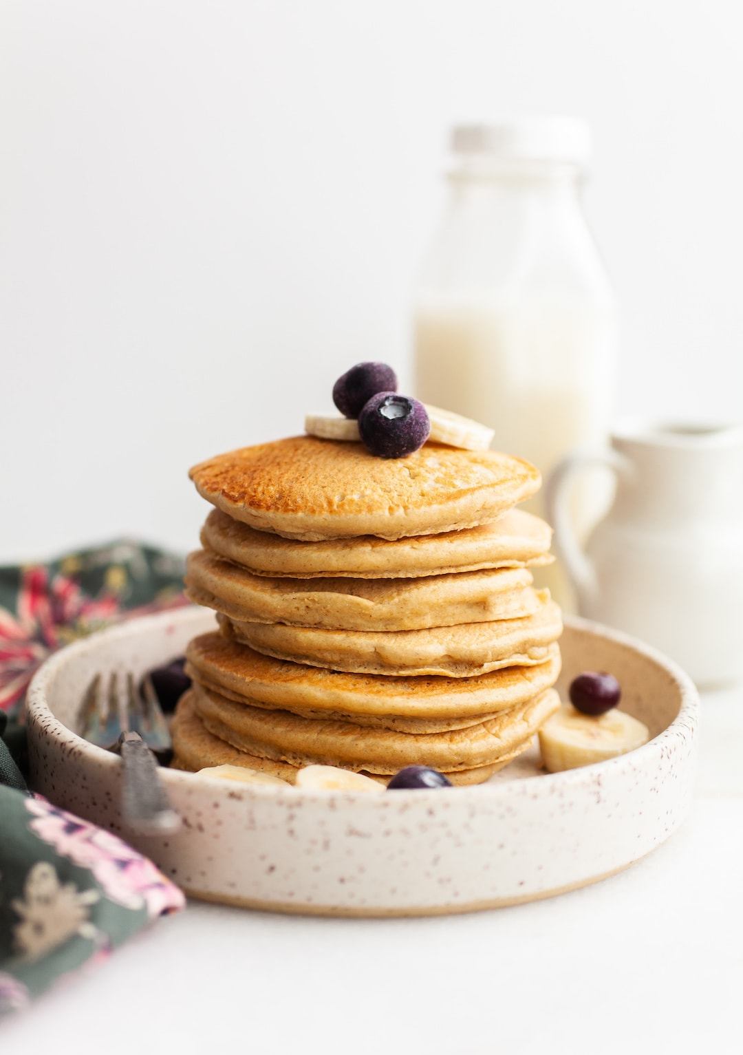 image of a stack of Fluffy Oat Flour Pancakes with a white backdrop