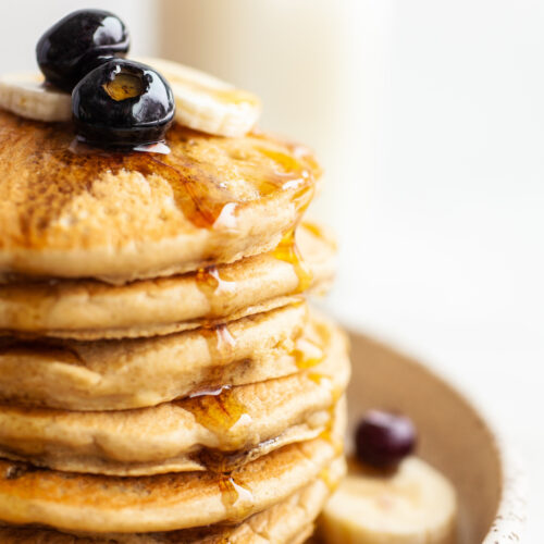 close up image of a stack of Fluffy Oat Flour Pancakes topped with maple syrup