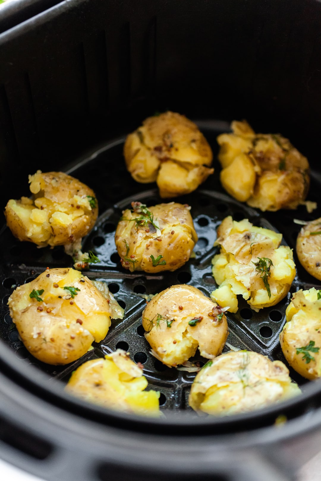image of an air fryer basket with smashed potatoes inside