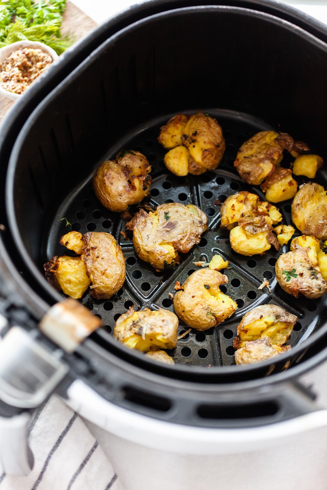 image of an air fryer basket filled with crispy smashed potatoes