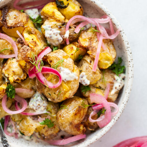 image of a plate topped with air fryer smashed potatoes and pickled red onions