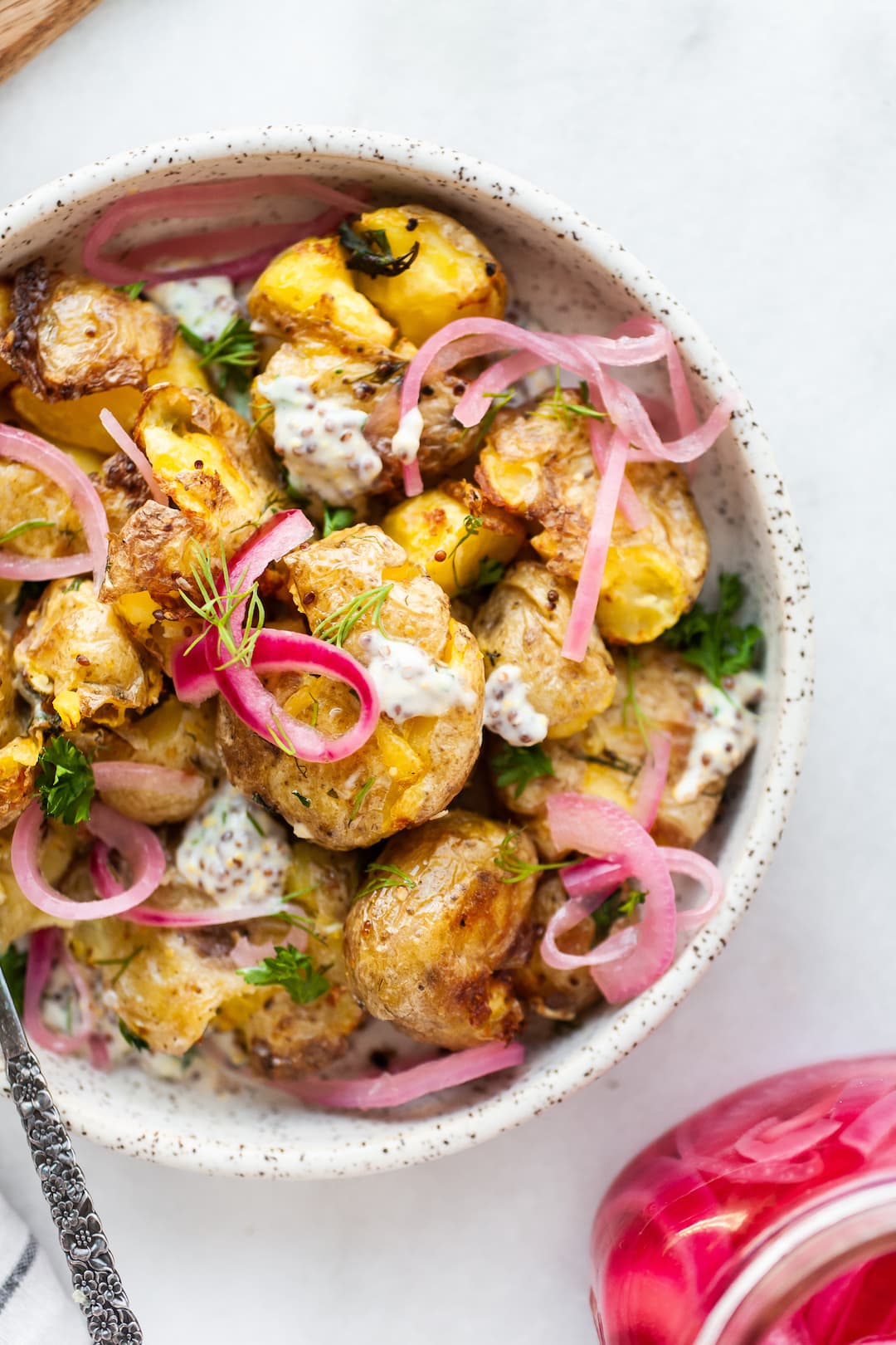 image of a plate topped with air fryer smashed potatoes and pickled red onions