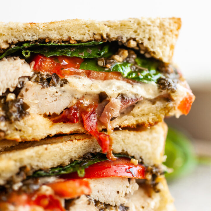 close up image of a turkey pesto sandwich with spinach and tomatoes