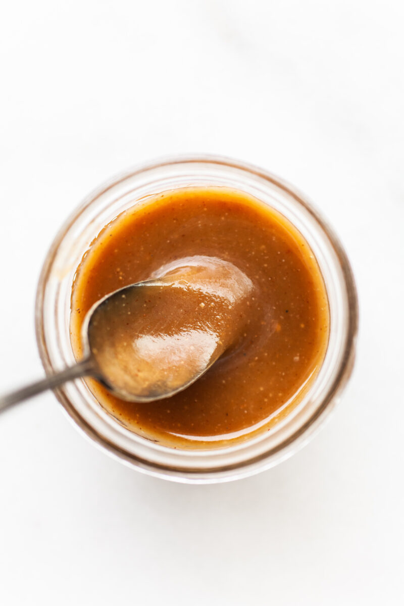 image of a jar with caramel sauce inside and a spoon dipping in