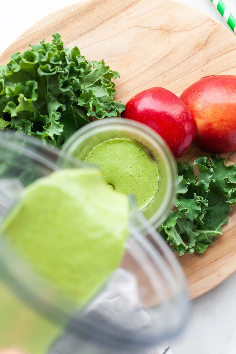 image of a blender canister pouring apple greens smoothie into a jar from overhead