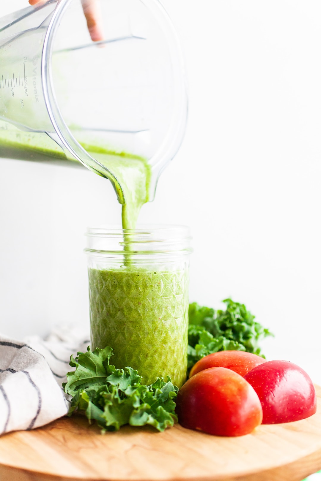 image of a blender canister pouring apple greens smoothie into a jar from overhead